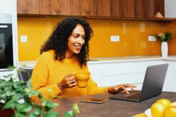 Woman with Curly Hair on Computer and Smiling