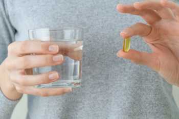 Man Holding Fish Oil Capsule and Water
