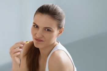 Disgusted Woman Holding Fish Oil