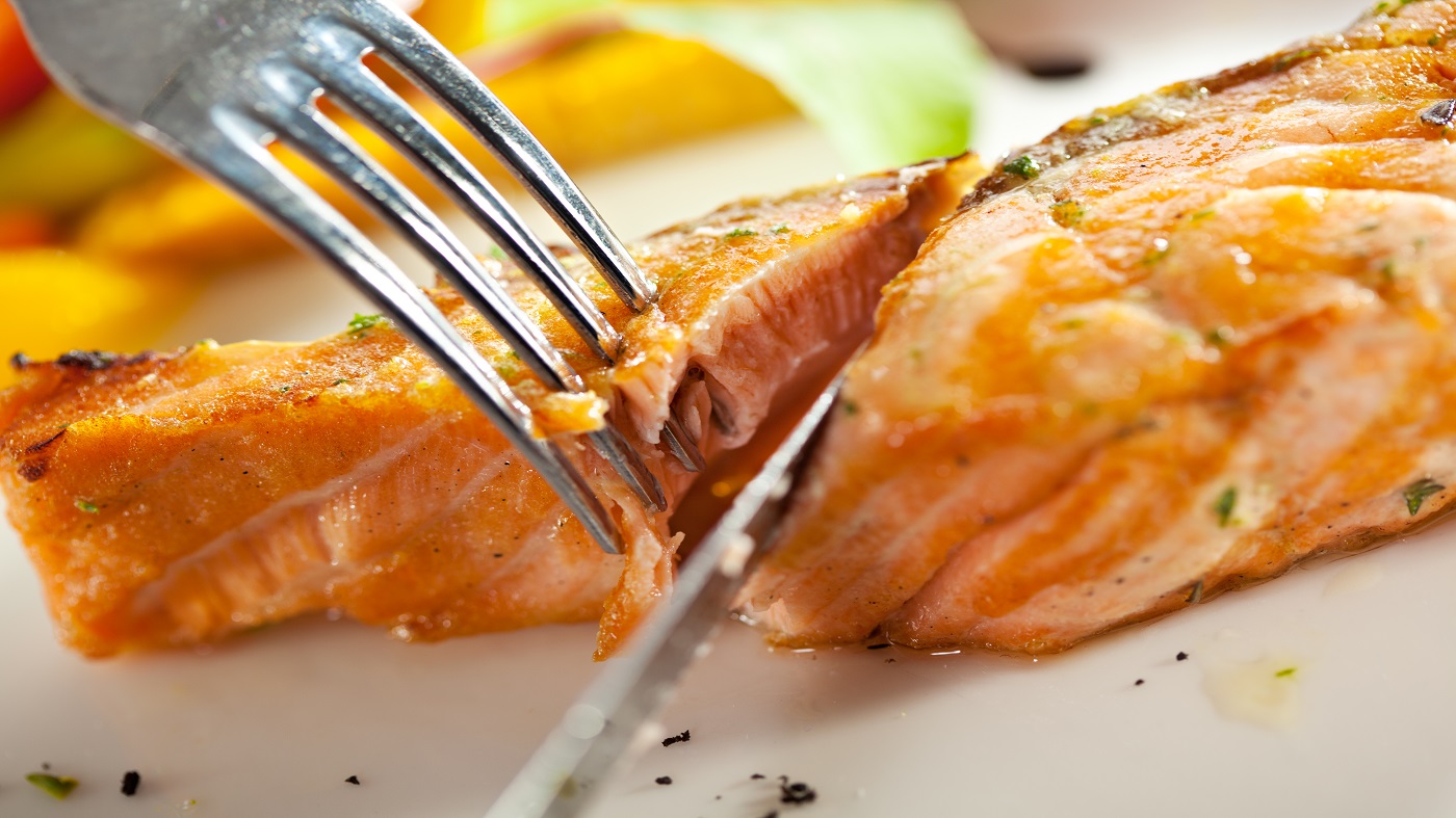 Wild Caught vs. Farm Raised Salmon -- salmon on a dinner plate with fork and knife