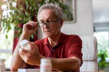 Elderly Man Reading Supplement Bottle