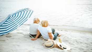 Elderly Couple Sitting on Beach Under Umbrella