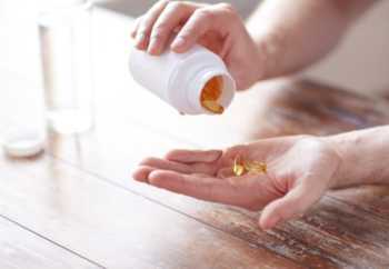 Fish Oil Supplements Poured from Bottle into Hand
