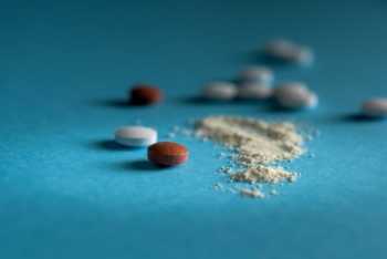 Whole Tablets and Crushed Tablet on Blue Table