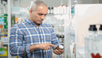 Man in Plaid Shirt Reading Supplement Bottle