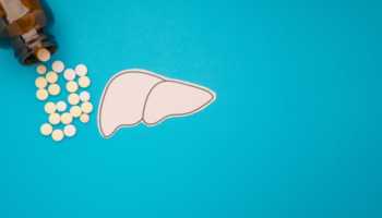 Liver Shape Made From Paper with Pills and Bottle Against Blue Background