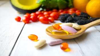 Getting Vitamins and Minerals from Food vs. Supplements -- fruits, vegetables, and a spoon containing supplements on a table