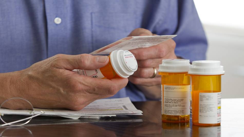 Supplement Interactions With Antibiotics -- man reading prescription bottle instructions