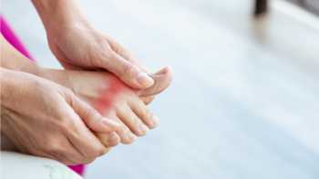 Woman with gout pain rubbing her foot near the big toe