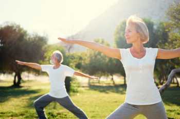 Elderly couple yoga pose in sunshine