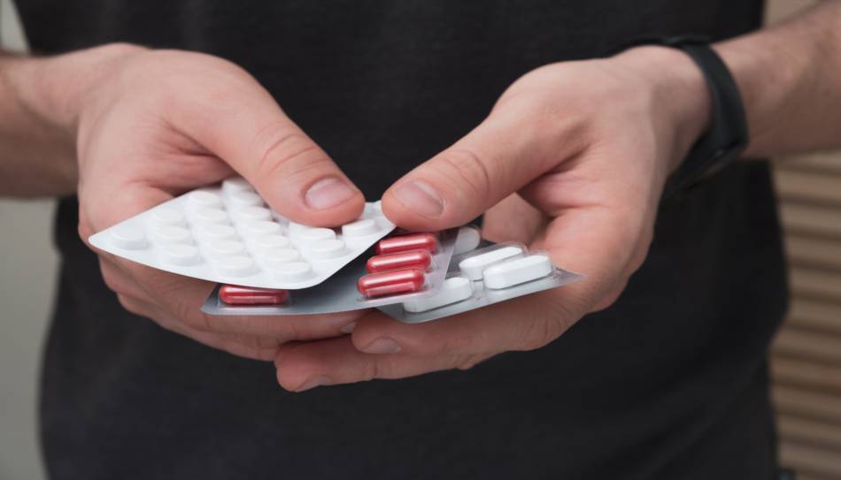 Man Holding Blister Packs of Supplements