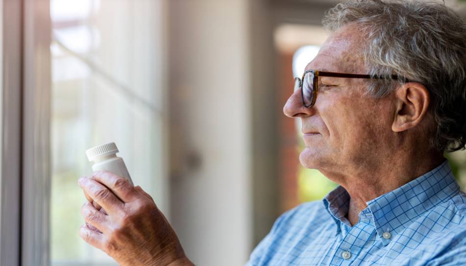Elderly Man Reading Supplement Bottle