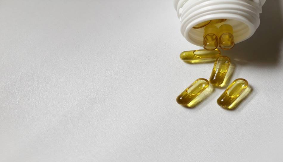 Olive Oil Capsules Falling Out of Bottle on White Background