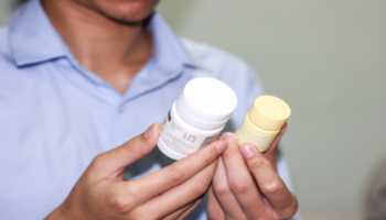 Man in Light Blue Comparing Supplement Bottles