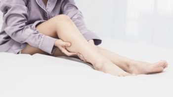 Woman in bed with leg cramp