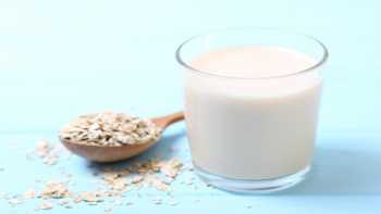 Is oatmeal milk healthy? -- glass of oatmeal milk and oats in a spoon