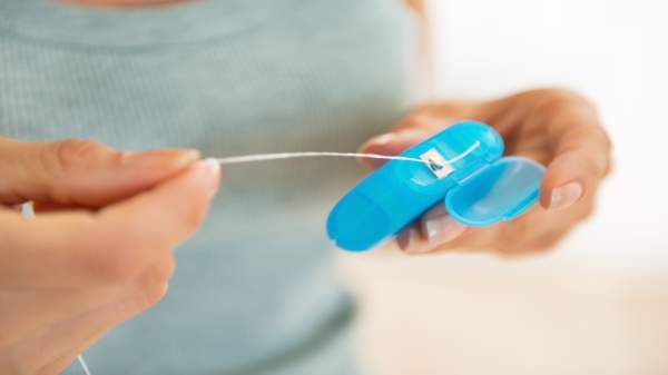Toxic PFAS Chemicals in Dental Floss -- Woman Looking at Dental Floss