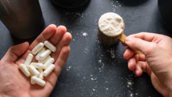 Hands holding essential amino acid capsules and protein powder