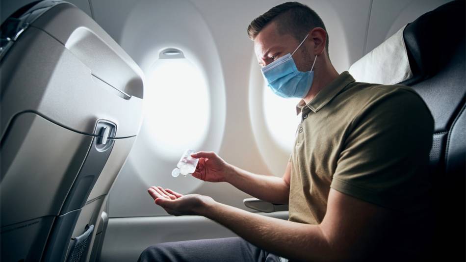 Is it safe to fly and how can I avoid getting COVID-19? -- Man on Airplane With Mask and Hand sanitizer