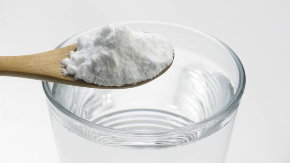Magnesium citrate in a spoon over a glass of water