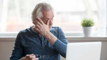 Older man with dry eye rubbing his eyes while holding his glasses