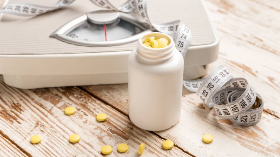 Container of natural appetite suppressant supplement with measuring tape and scale in background