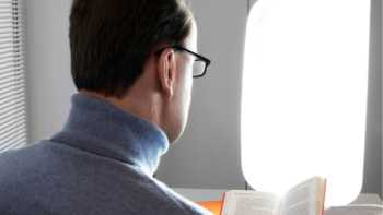 Man reading a book while sitting in front of a light box