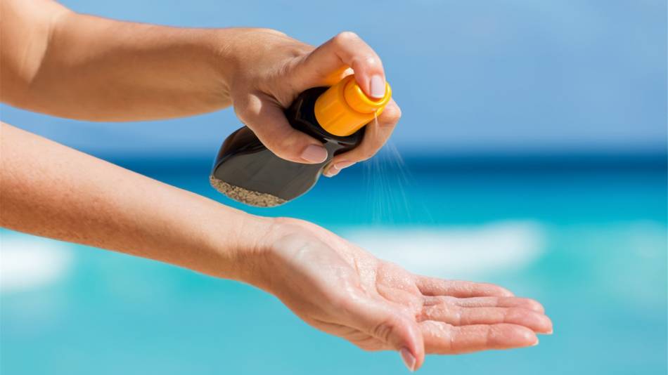 Benzene in Suncreen -- Spraying Sunscreen Onto Hand on the Beach