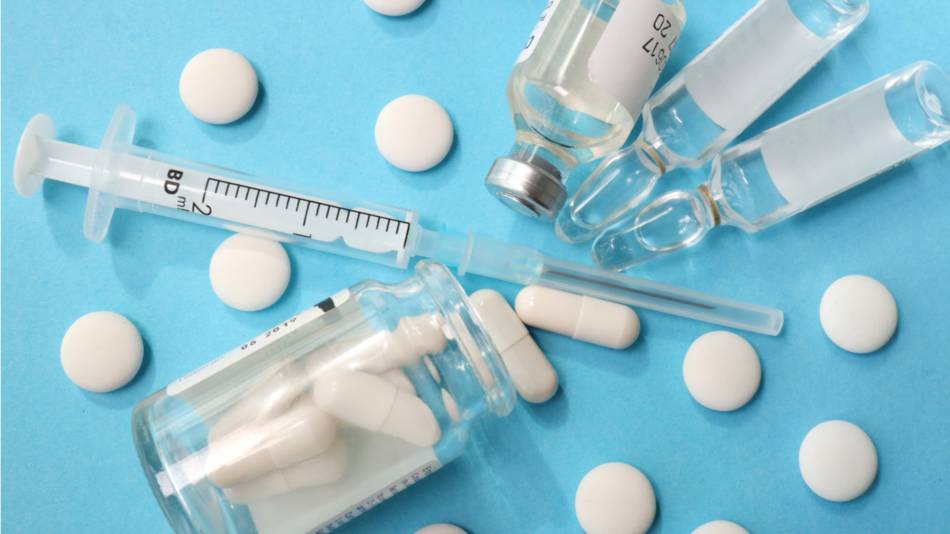 White capsules vials and a syringe on a blue background