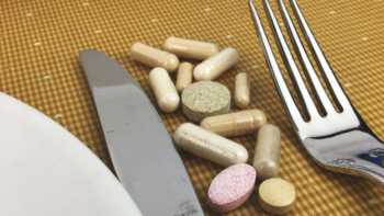 Digestive enzyme supplements placed on a table between a fork and knife