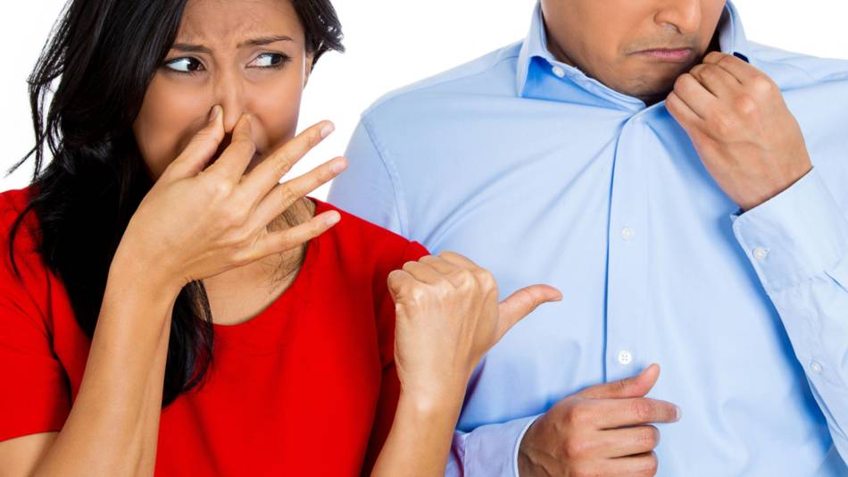 Woman holding her nose and pointing to a man with body odor