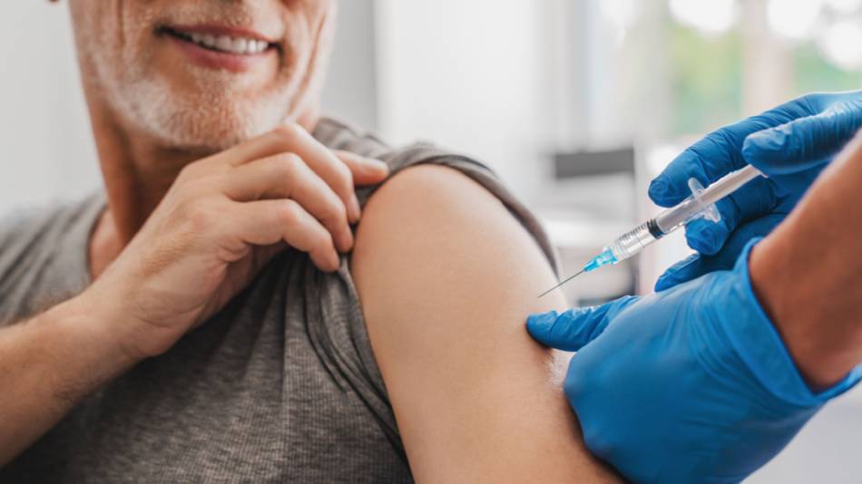 Older man in gray t-shirt getting vaccinated for COVID-19