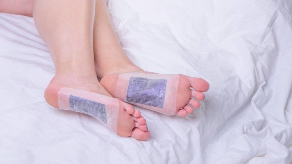 Woman lying in bed wearing detox foot pads