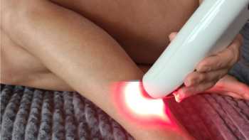 Woman using a red light device on her lower leg
