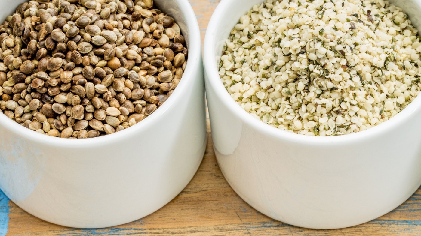 Whole hemp seeds and hemp hearts in small white bowls