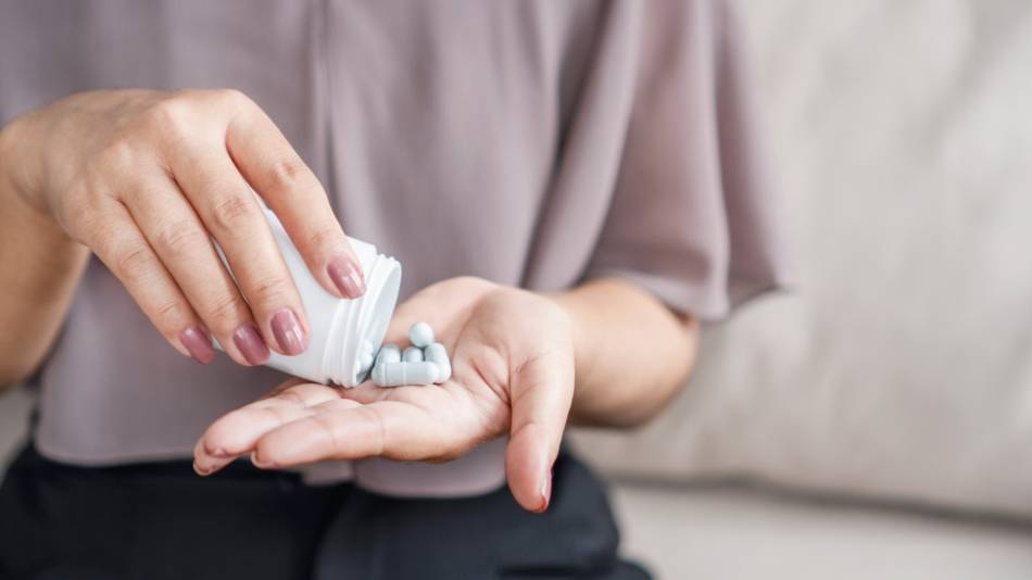 Woman pouring capsules of Akkermansia muciniphila into her hand