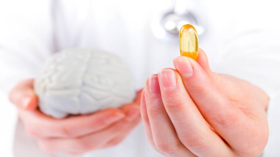 Supplements for Memory -- doctor holding a model of a brain and fish oil capsule